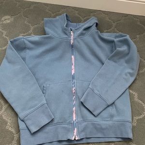 This is a used athleta girl zip up hoodie. There is only 1 noticeable stain.